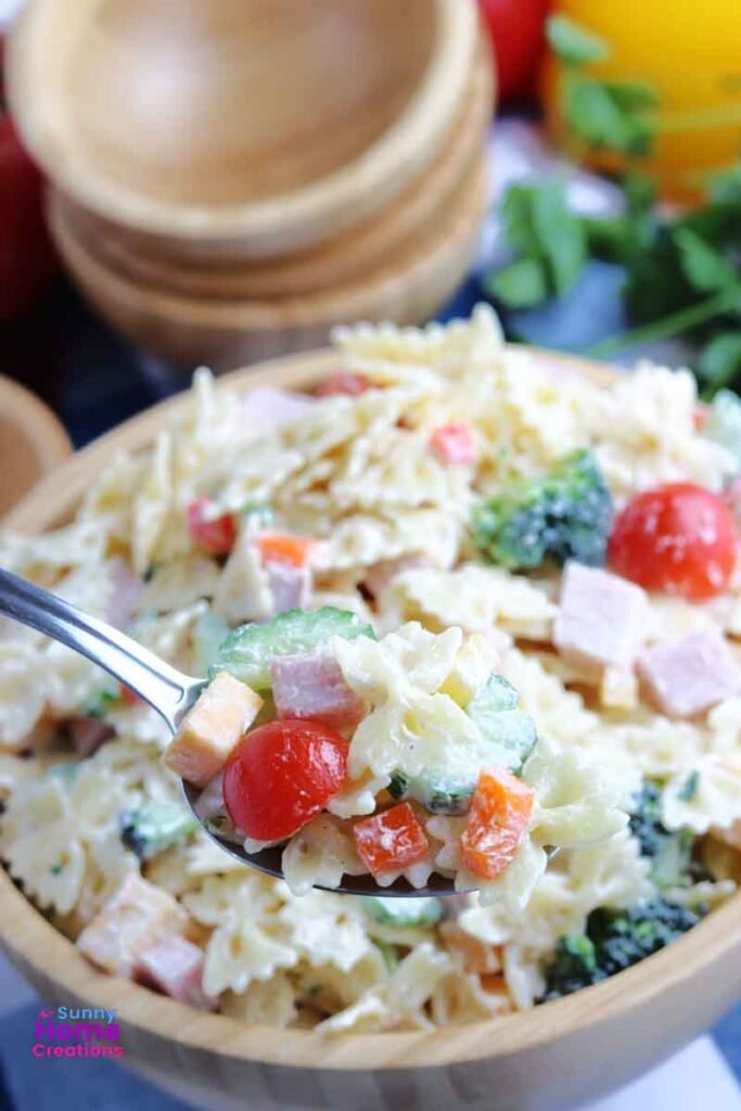 Big bowl of pasta salad with a heaping spoonful of pasta salad the main focus.
