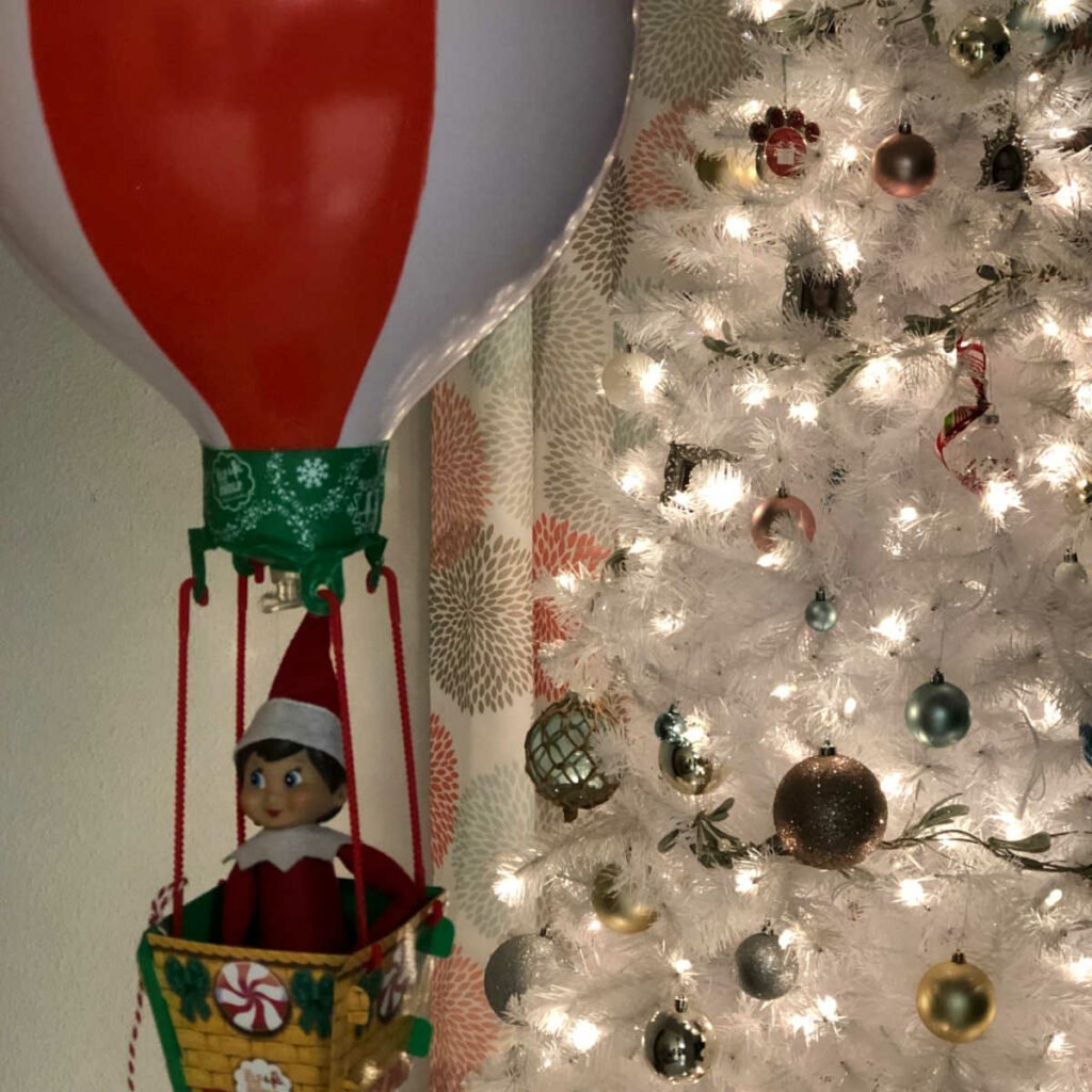 Elf on the Shelf in the basket of a hot air balloon.